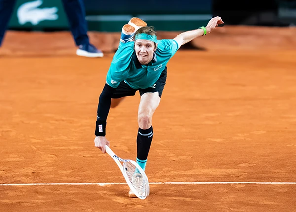 Alexander Bublik hits a serve at Roland Garros